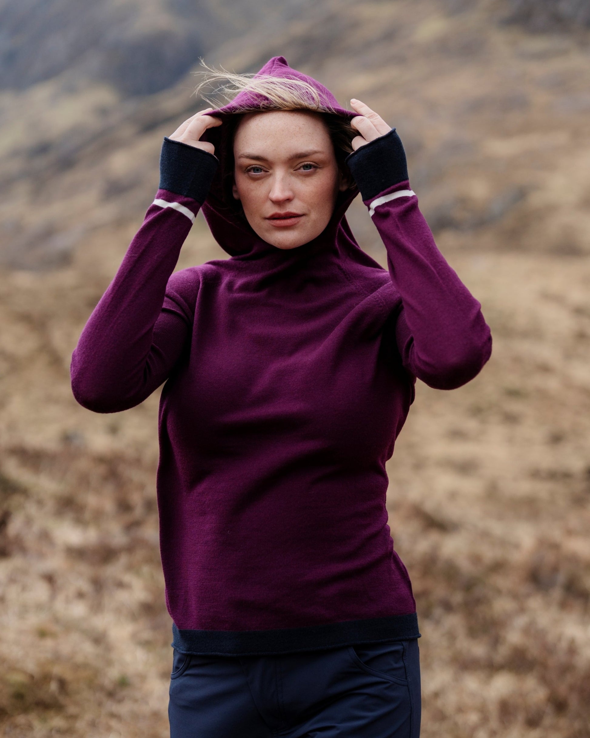 Person wearing a purple hoodie in a mountainous landscape