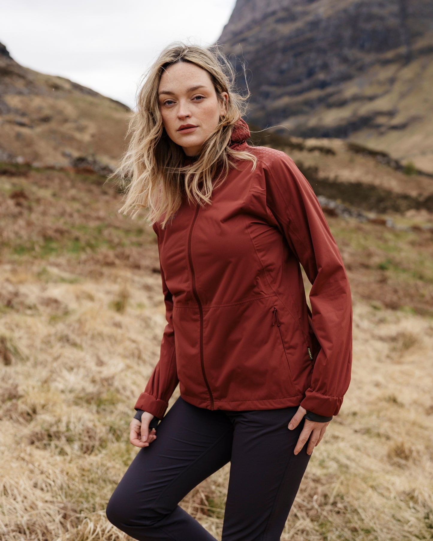 Woman wearing a red jacket standing in a mountainous landscape