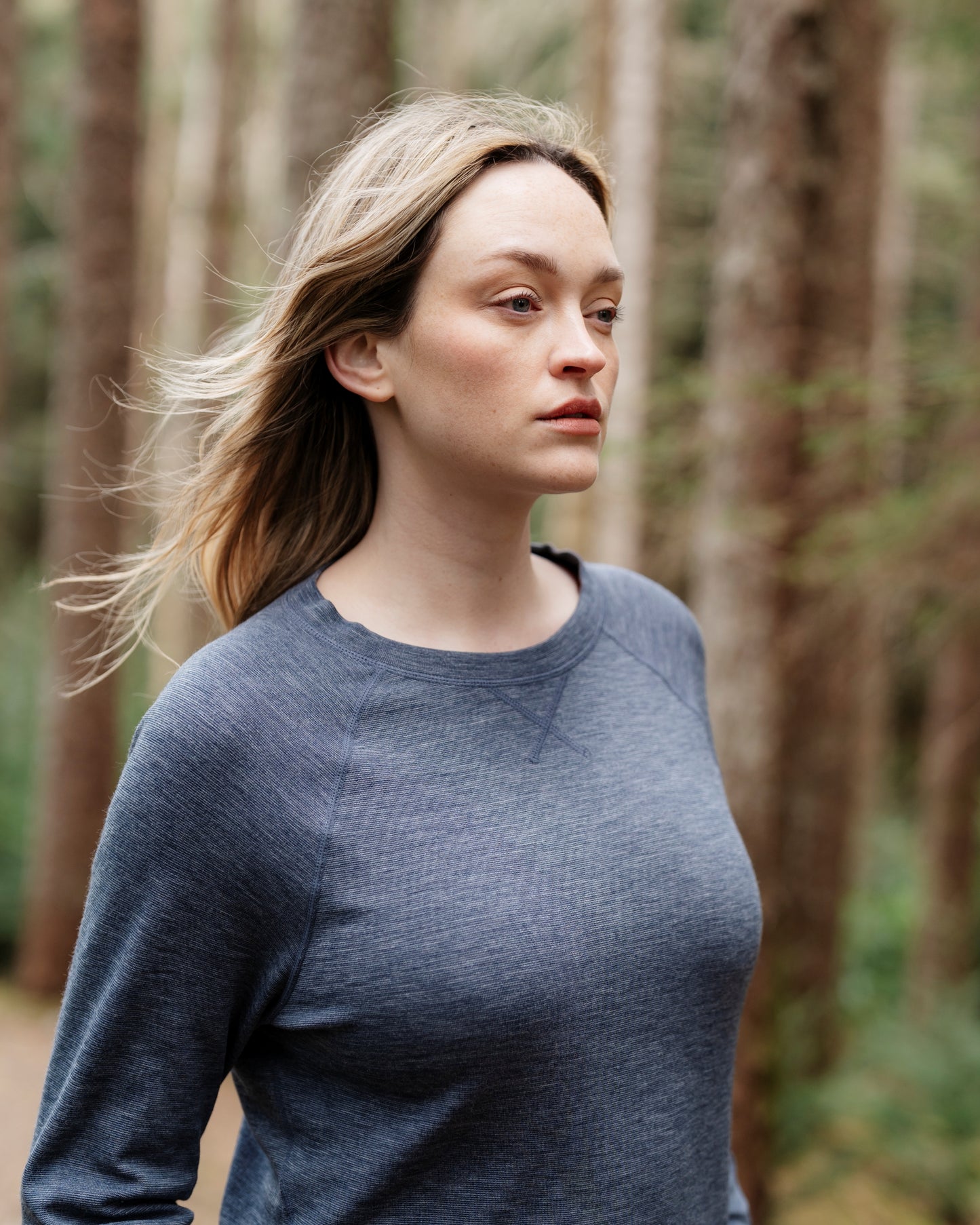Woman wearing a blue sweater standing in a forest