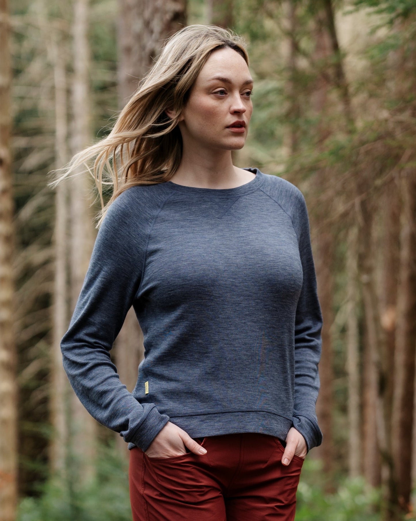 Woman walking on a forest path wearing a blue sweater and red shorts.