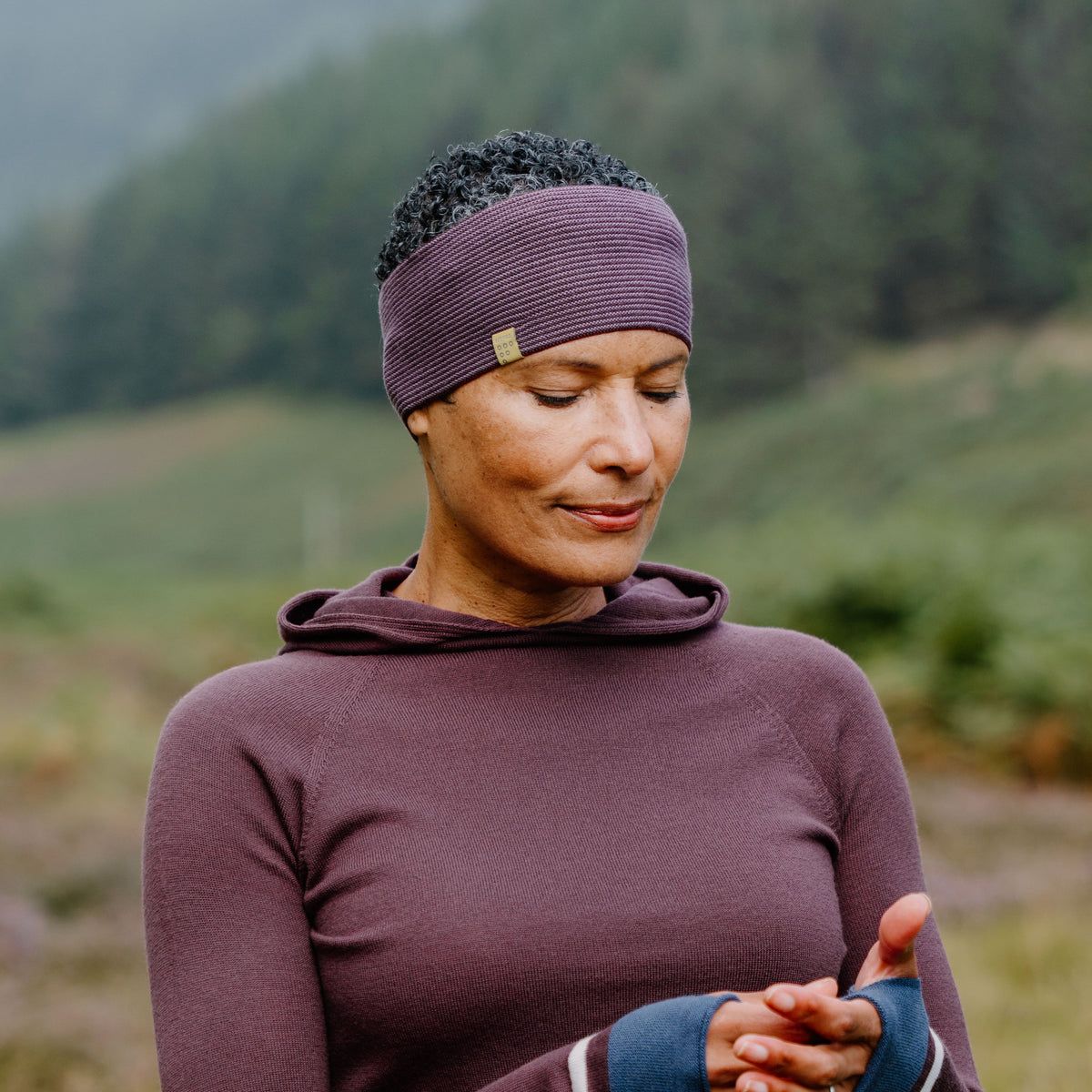Woman in the outdoors wearing a mulberry top with a striped merino wool headband