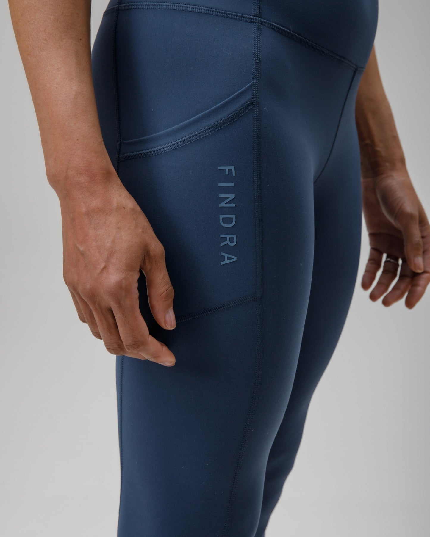 Navy blue leggings with 'FINDRA' branding on a light gray background