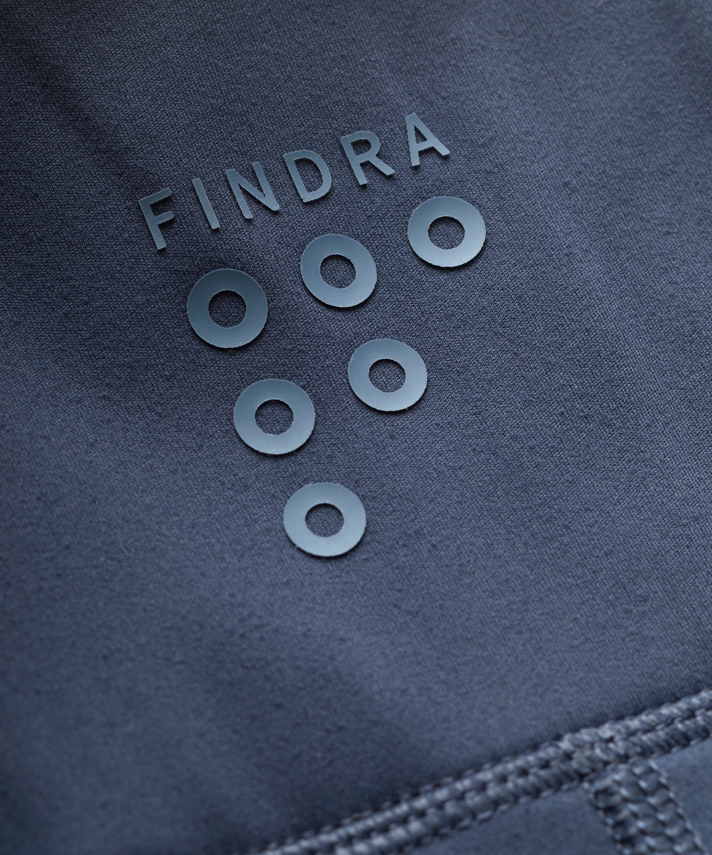 Close-up of a dark blue fabric with 'FINDRA' branding and circular elements.