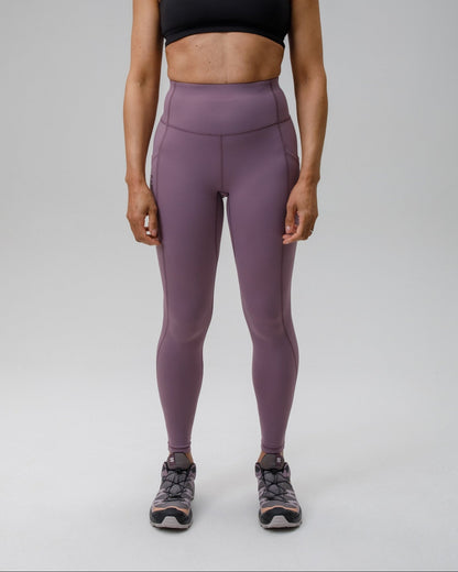 Woman wearing a black sports bra and purple FINDRA performance leggings on a grey background