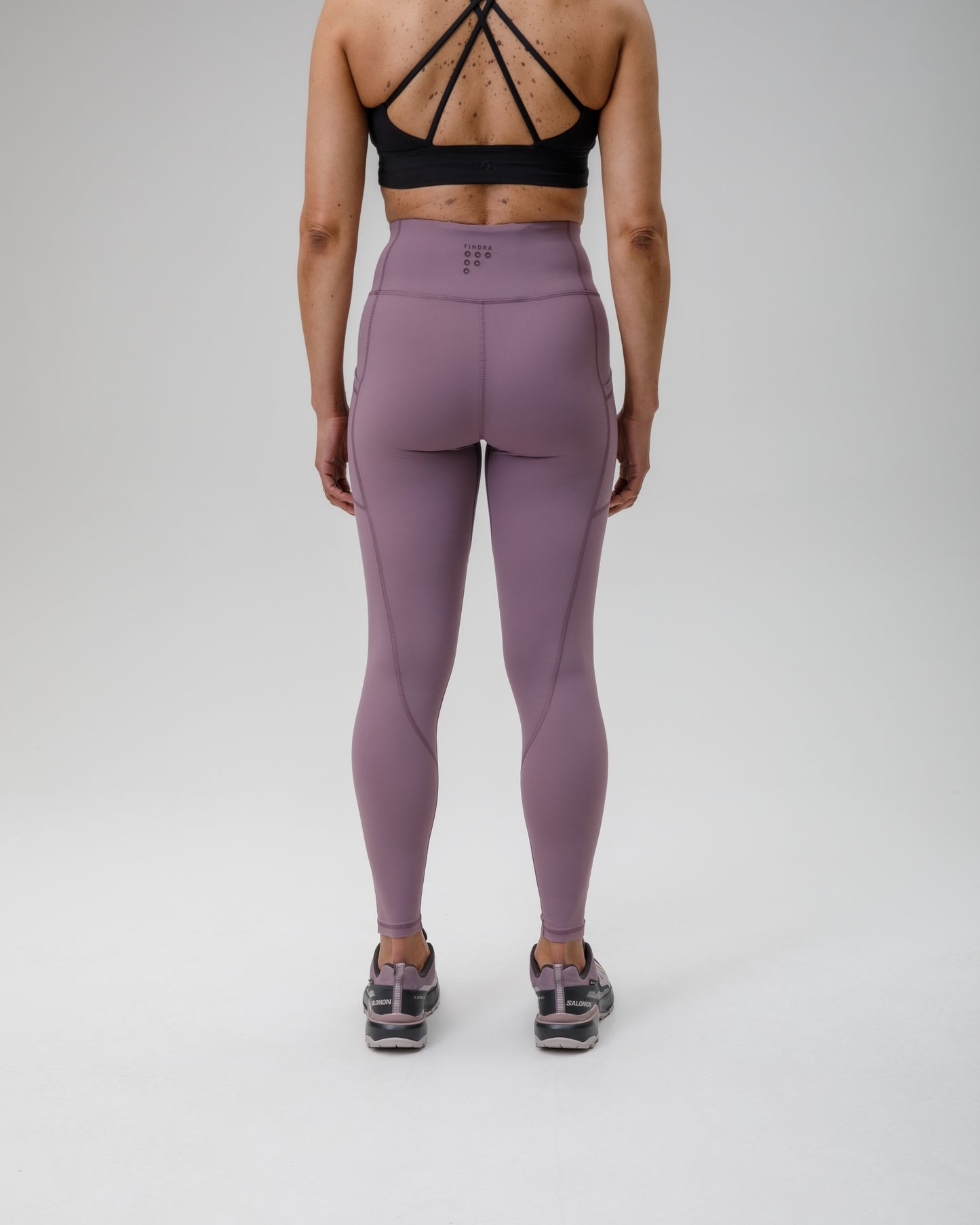 Person wearing purple FINDRA  leggings and black sports bra on a white background