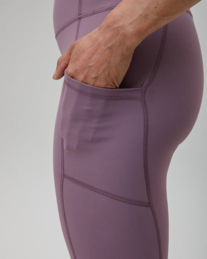 Purple leggings with a thigh pocket on a gray background