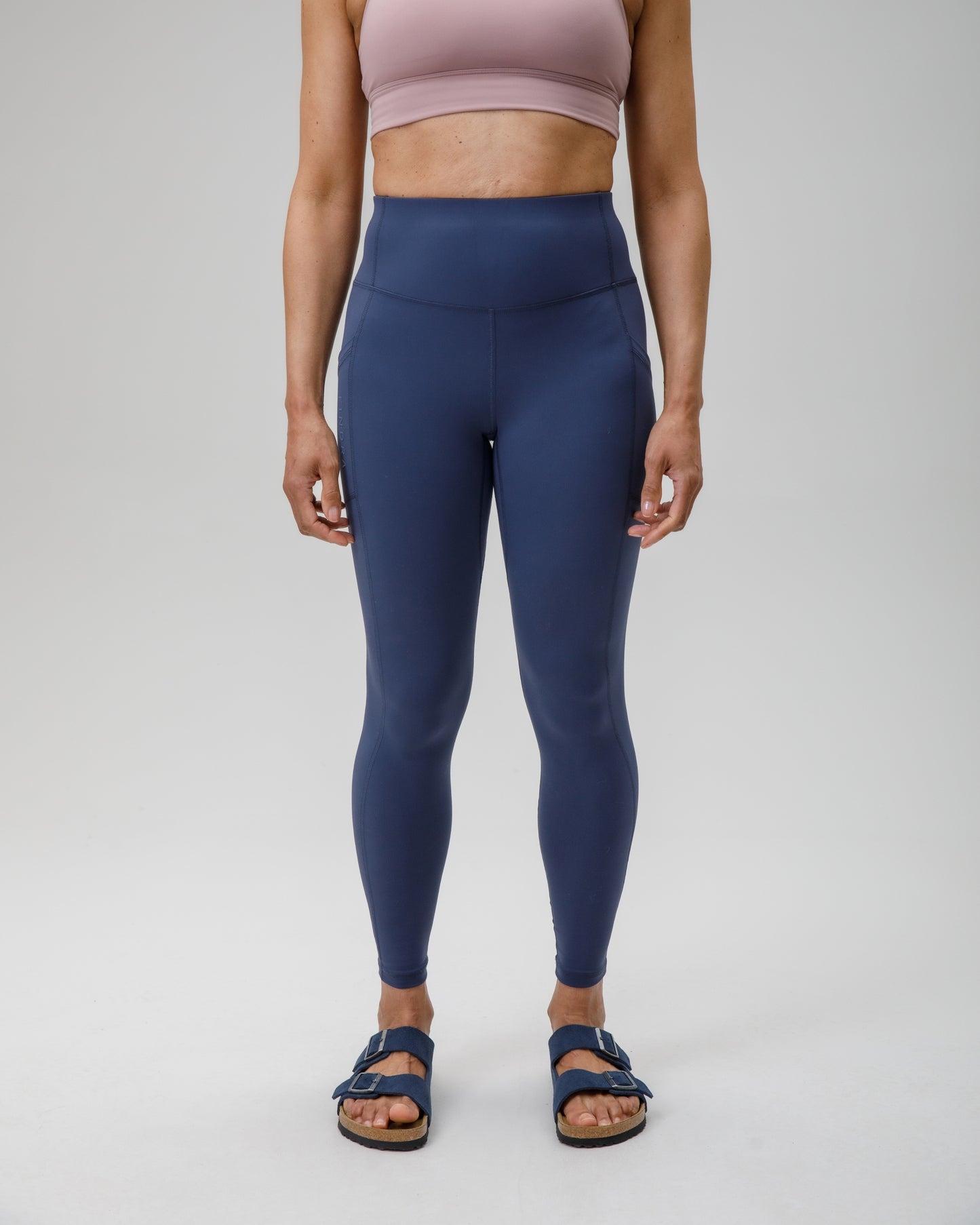 Person wearing blue leggings and a pink sports bra on a white background