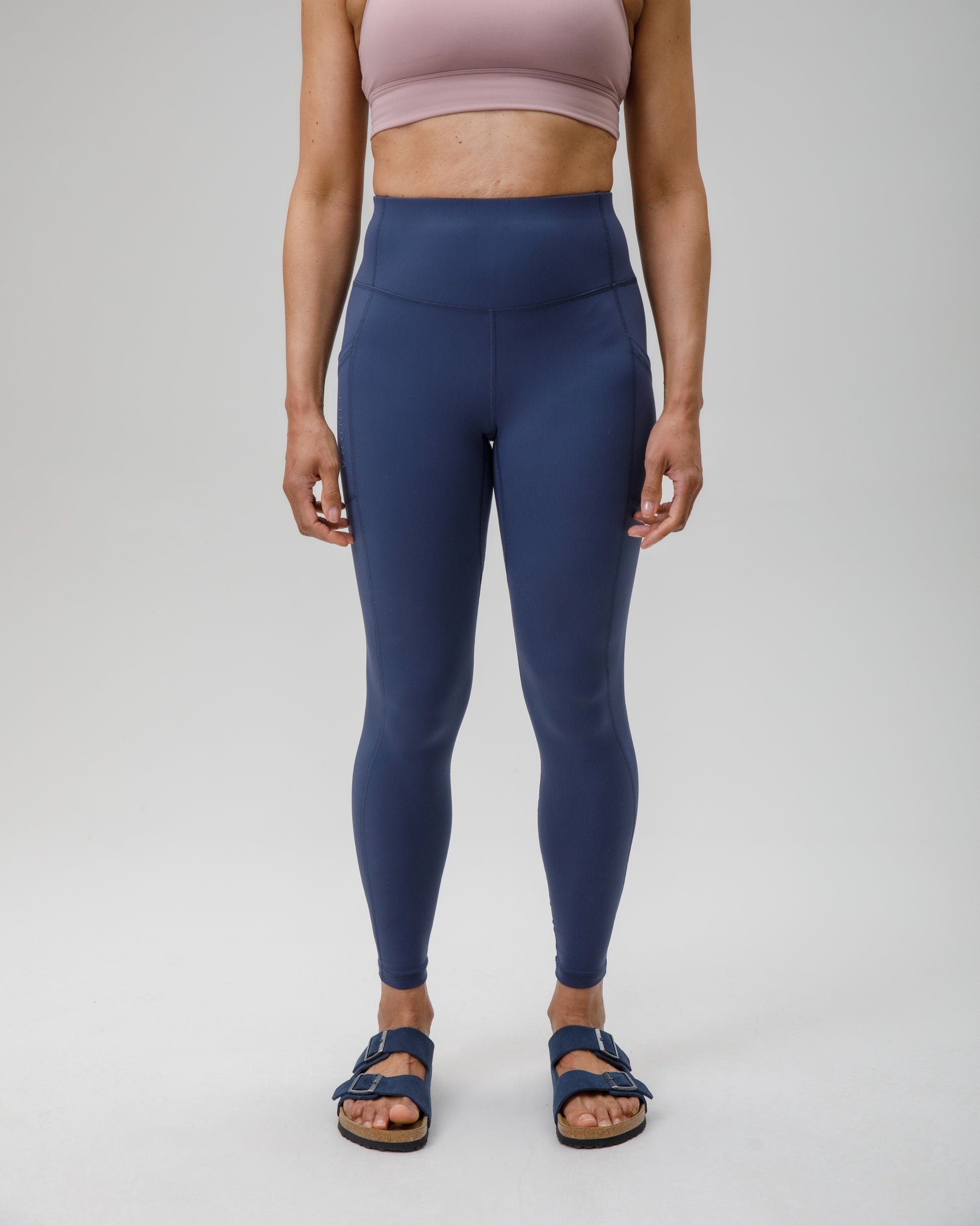 Person wearing blue leggings and a pink sports bra on a white background