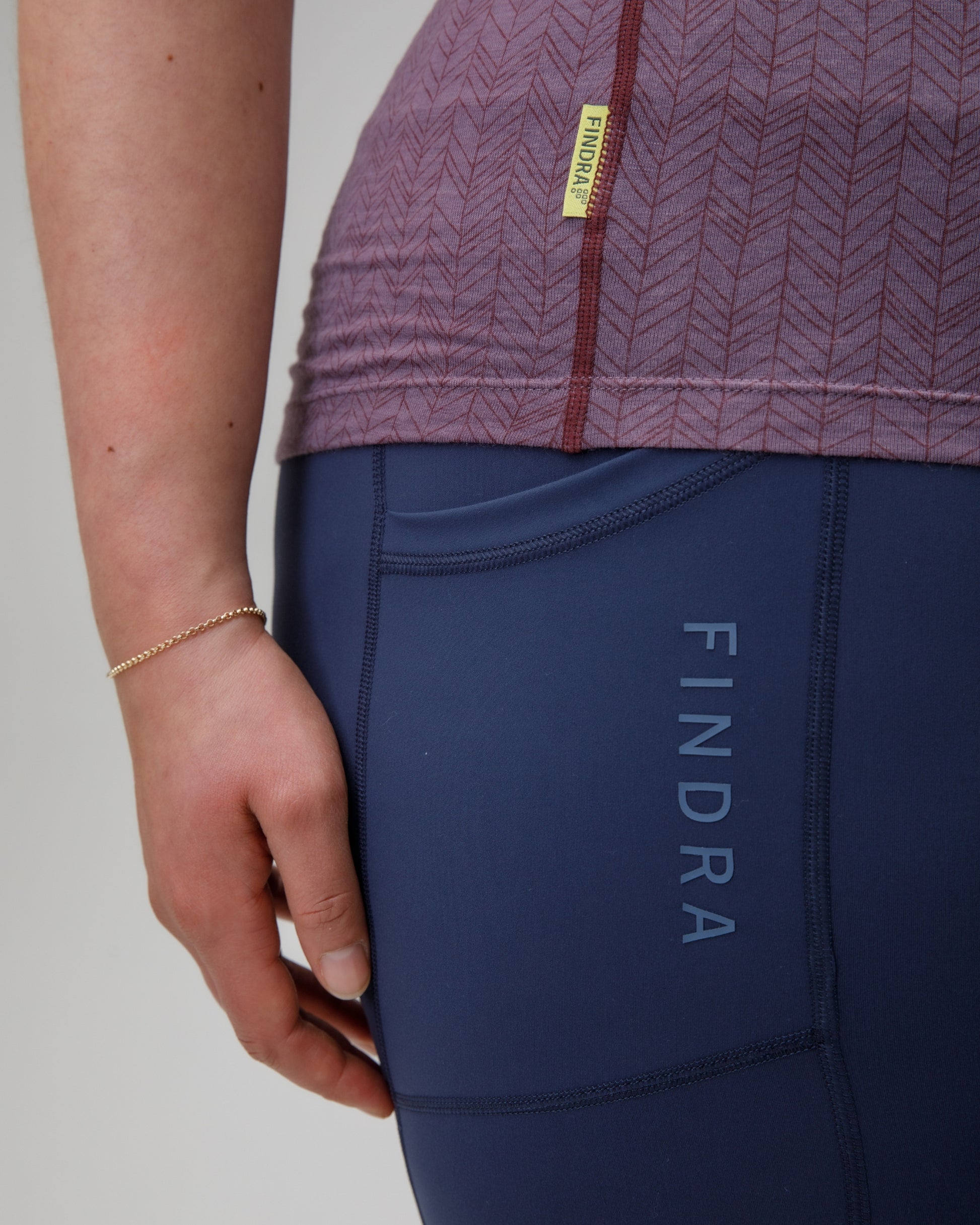 Person wearing a Purple merino vest top and blue leggings with 'Findra' branding on a gray background