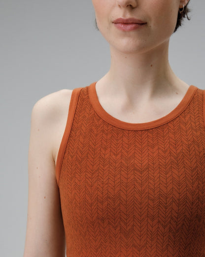 Woman wearing a rust-colored knitted tank top against a gray background