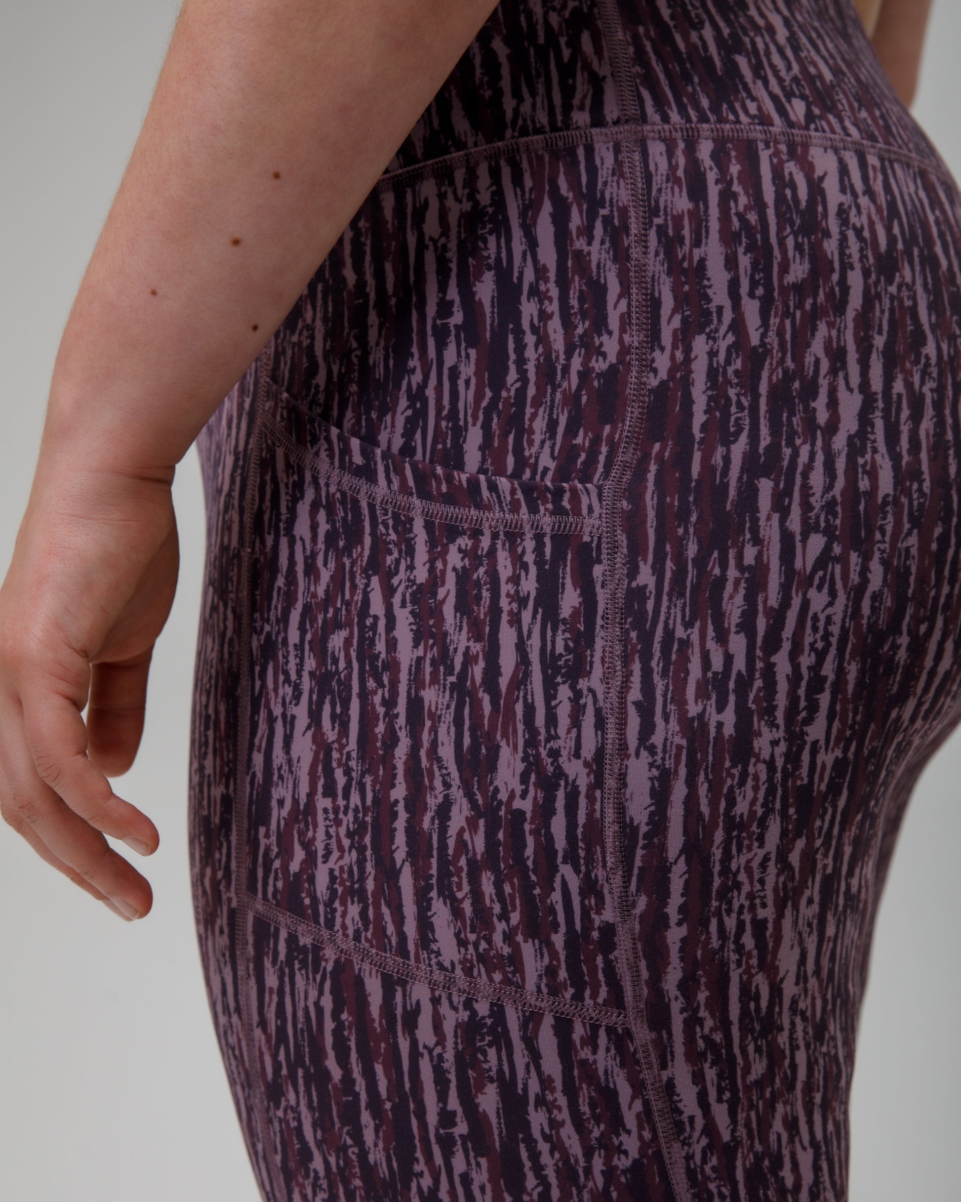 Close-up of a person wearing purple technical leggings  on a plain background