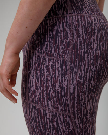 Close-up of a person wearing purple technical leggings  on a plain background