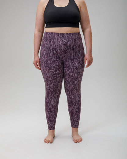 Person wearing FINDRA purple patterned technical leggings and black sports bra on a gray background