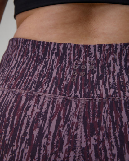 Close-up of a person wearing patterned leggings with a FINDRA logo on the waistband.