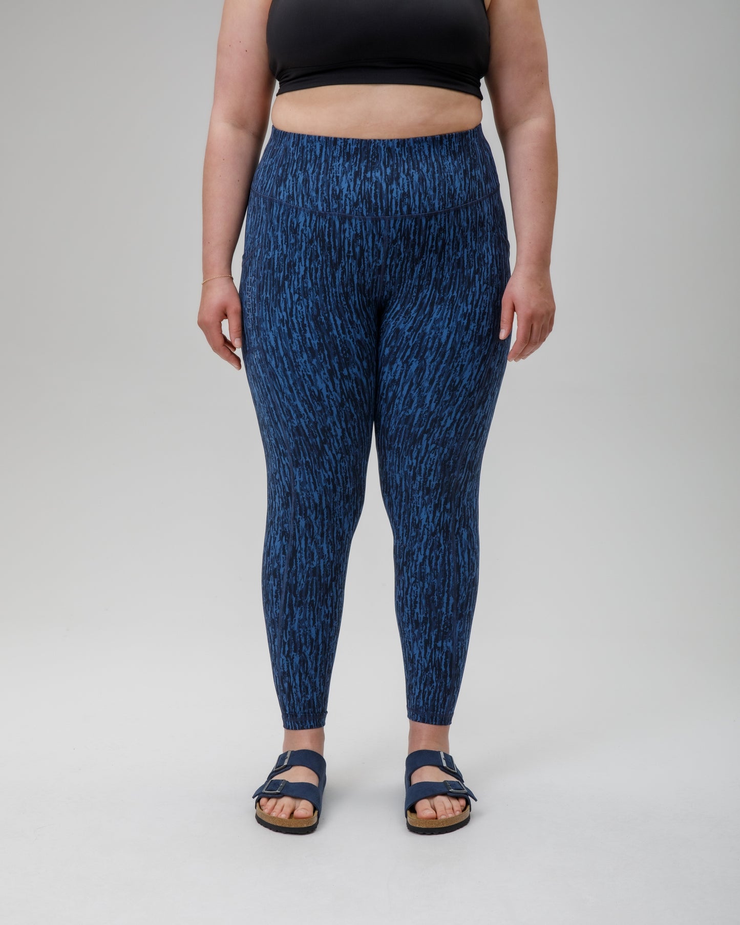 Person wearing blue patterned performance leggings on a white background