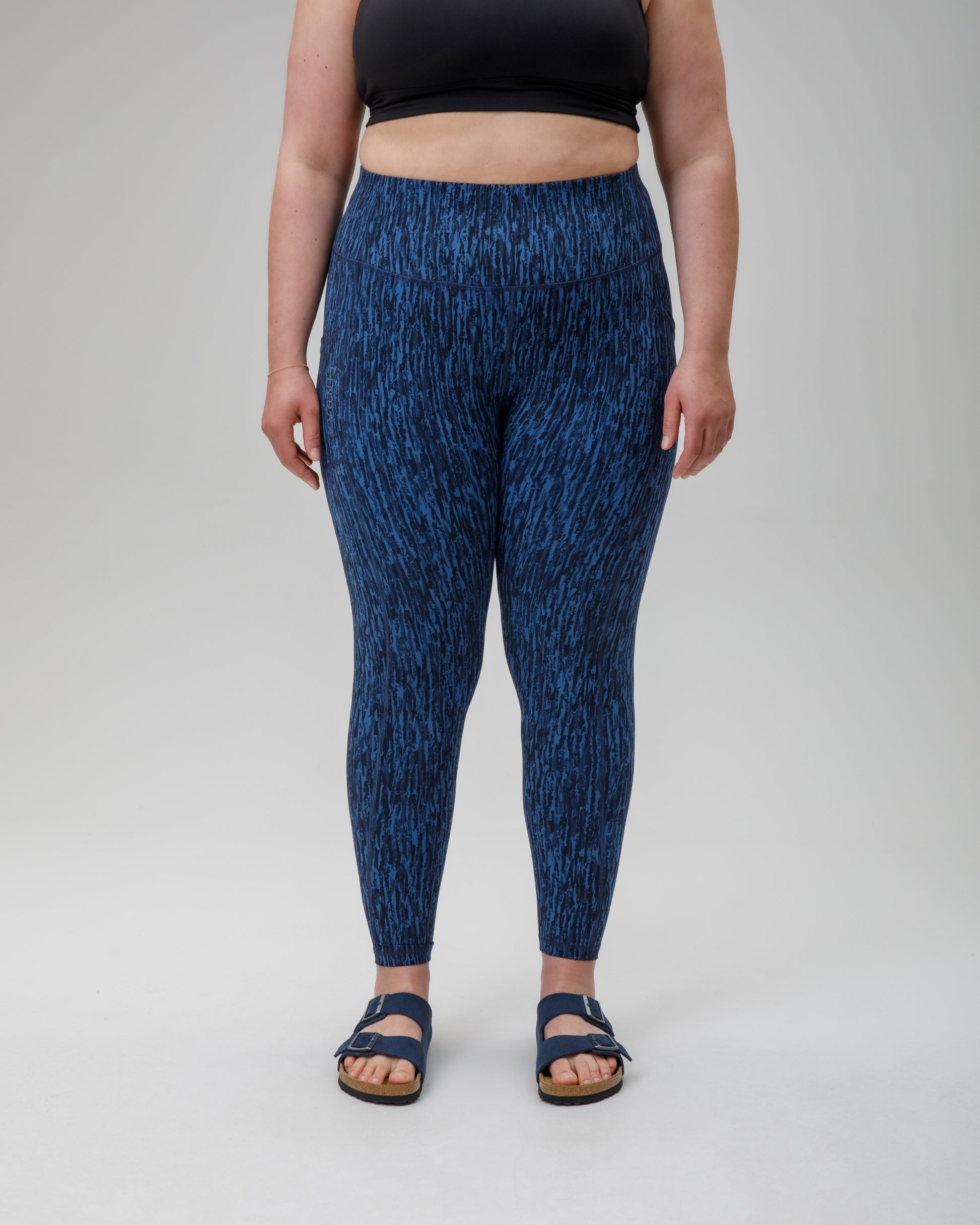 Person wearing blue patterned performance leggings on a white background
