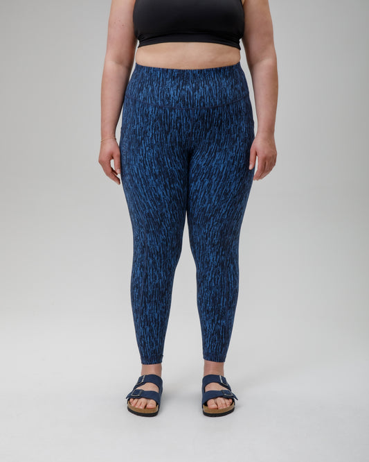 Person wearing blue patterned performance leggings on a white background