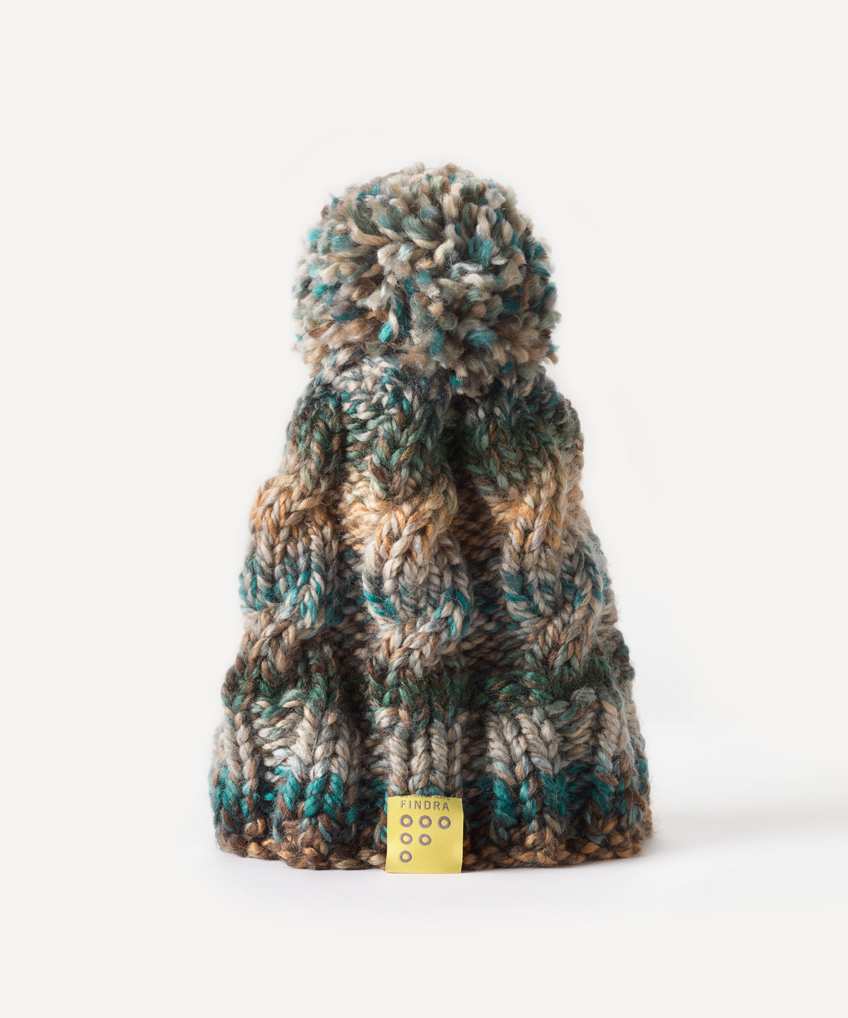 A chunky knit bobble hat with a large pom-pom, featuring a variegated color pattern of teal, brown, beige, and gray. A small yellow tag with the brand name 'FINDRA' is visible at the bottom.