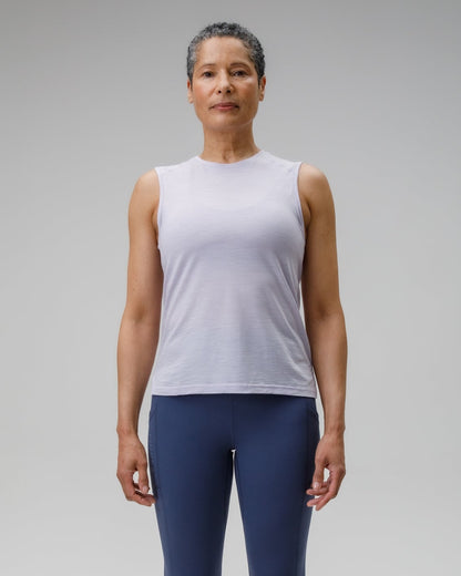 Person wearing a white sleeveless top and blue leggings on a gray background