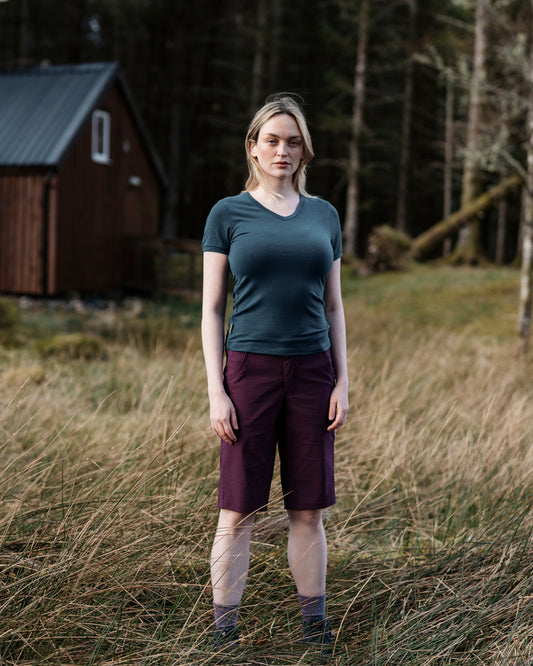 Woman standing in a field with a wooden cabin in the background