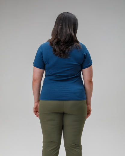 Person wearing a blue t-shirt and green pants against a gray background