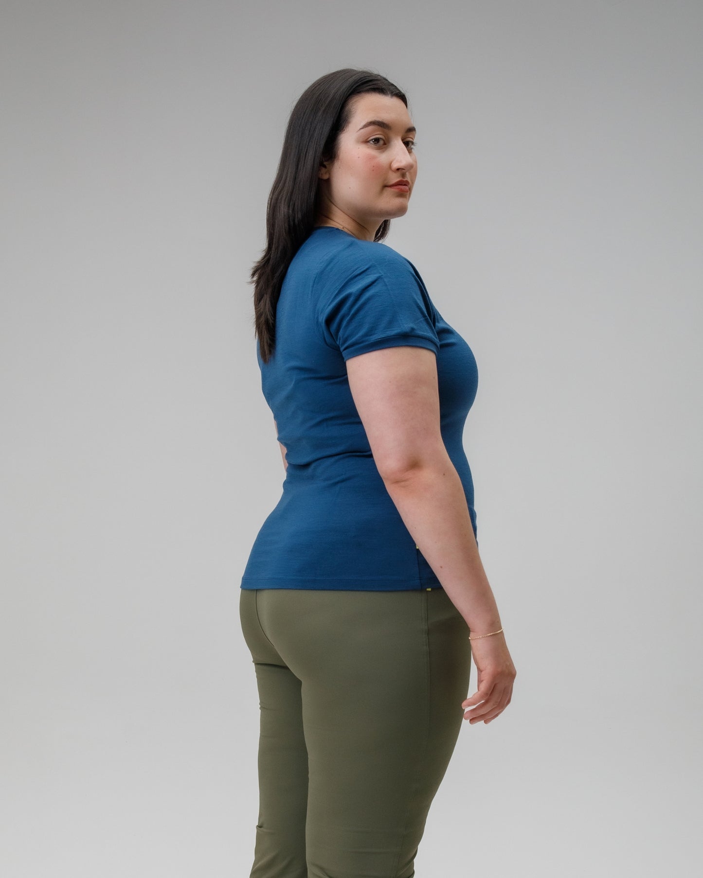 Woman wearing a blue shirt and green pants on a gray background