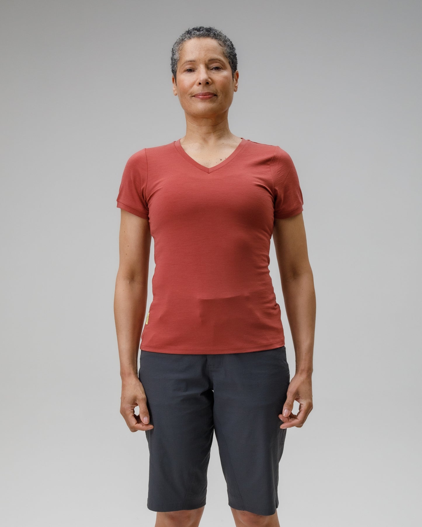 Person wearing a red t-shirt and dark shorts on a gray background