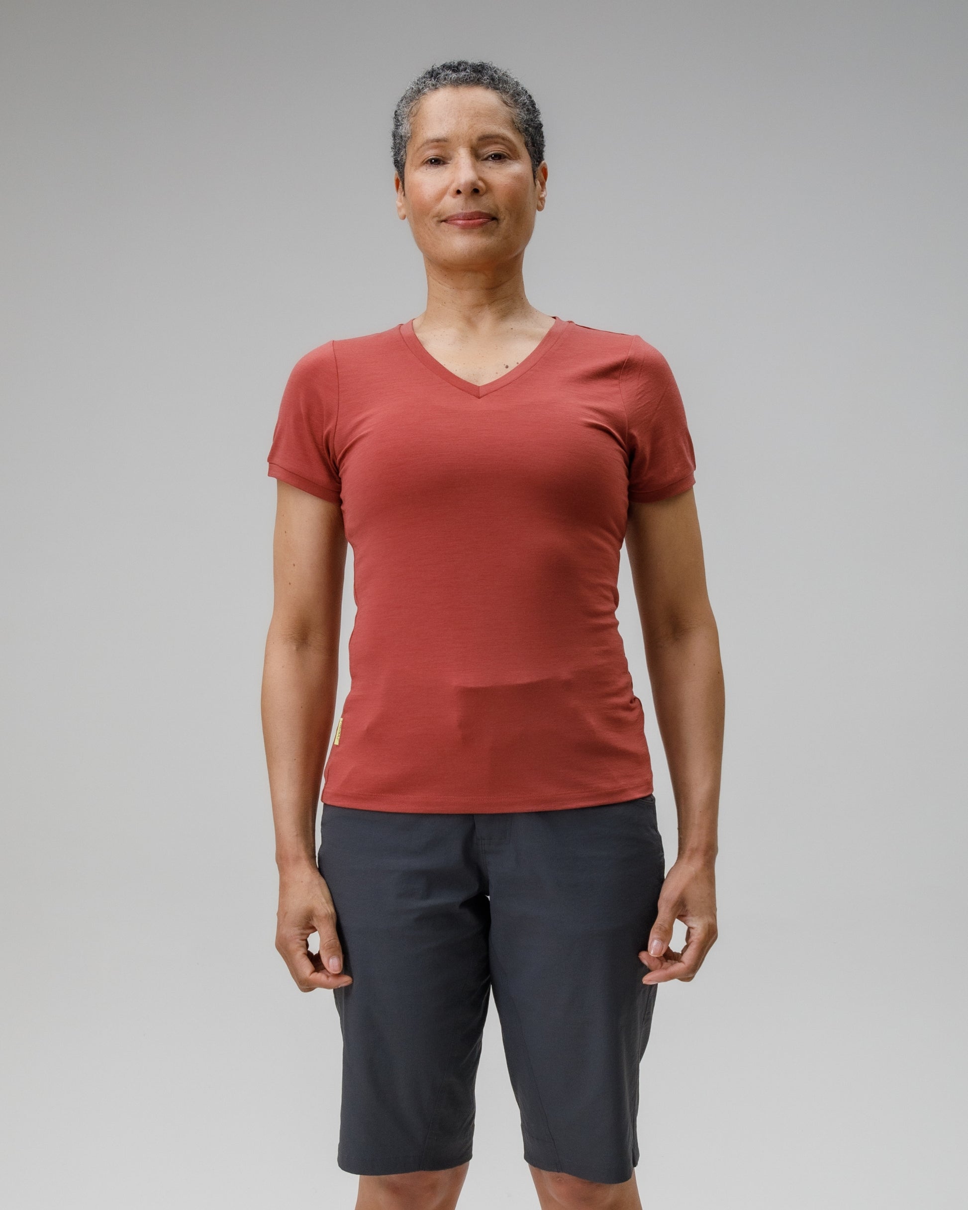 Person wearing a red t-shirt and dark shorts on a gray background