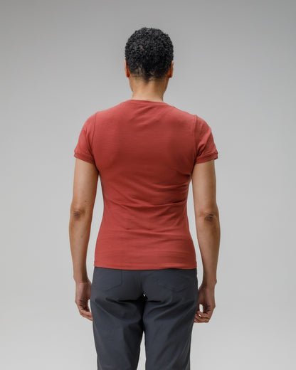 Person wearing a red t-shirt and dark pants on a gray background