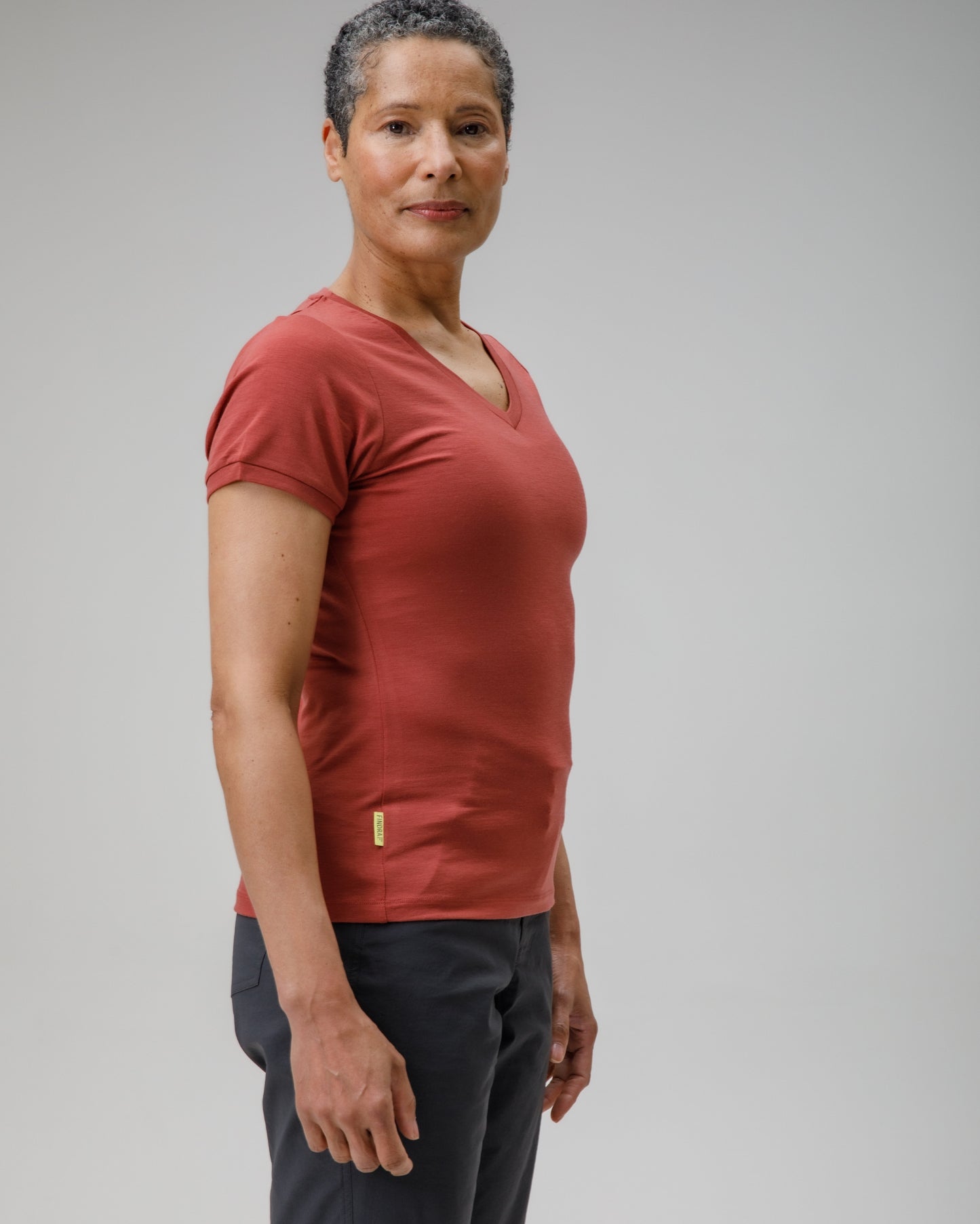 Woman wearing a red shirt and grey shorts against a plain background