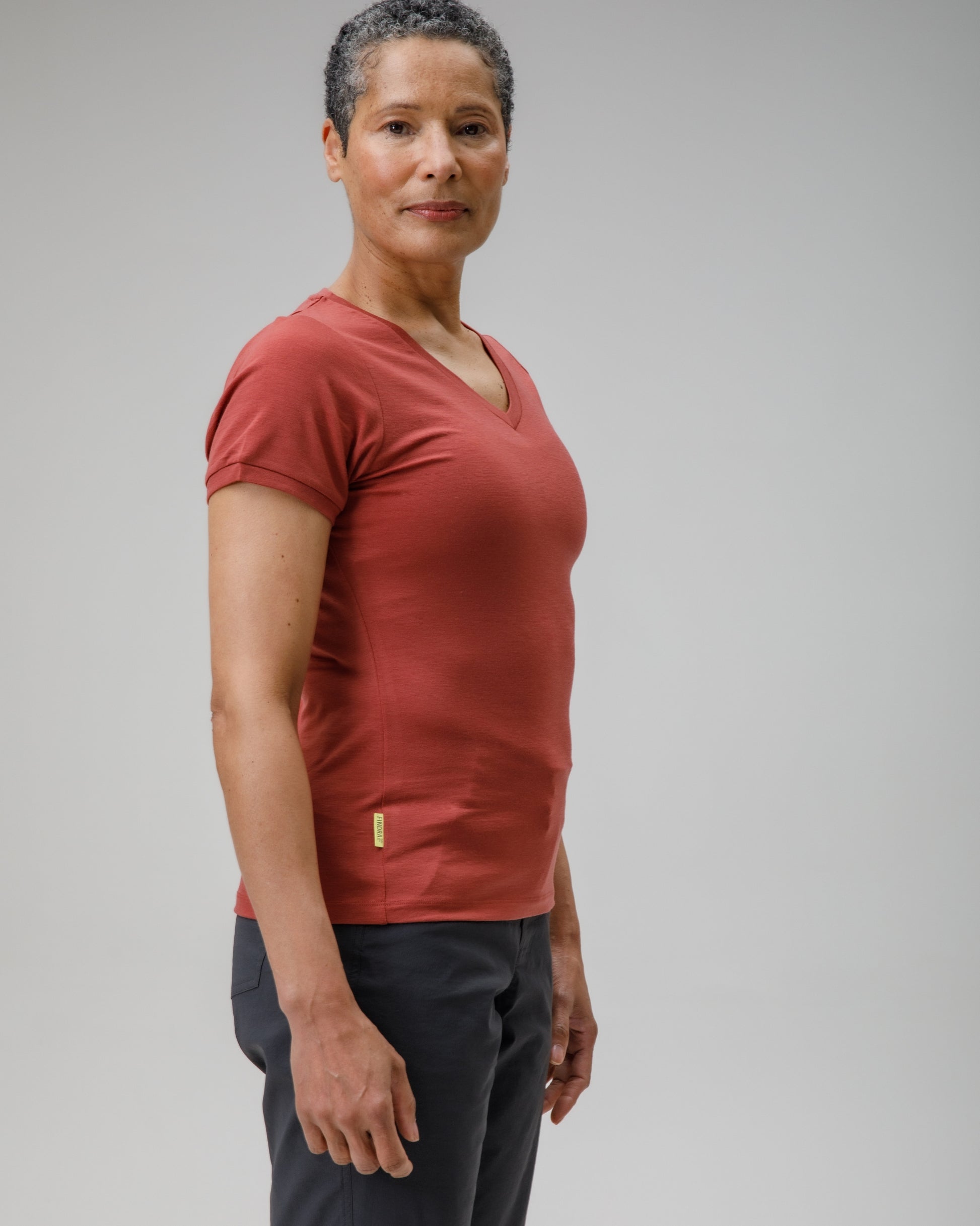 Woman wearing a red shirt and grey shorts against a plain background