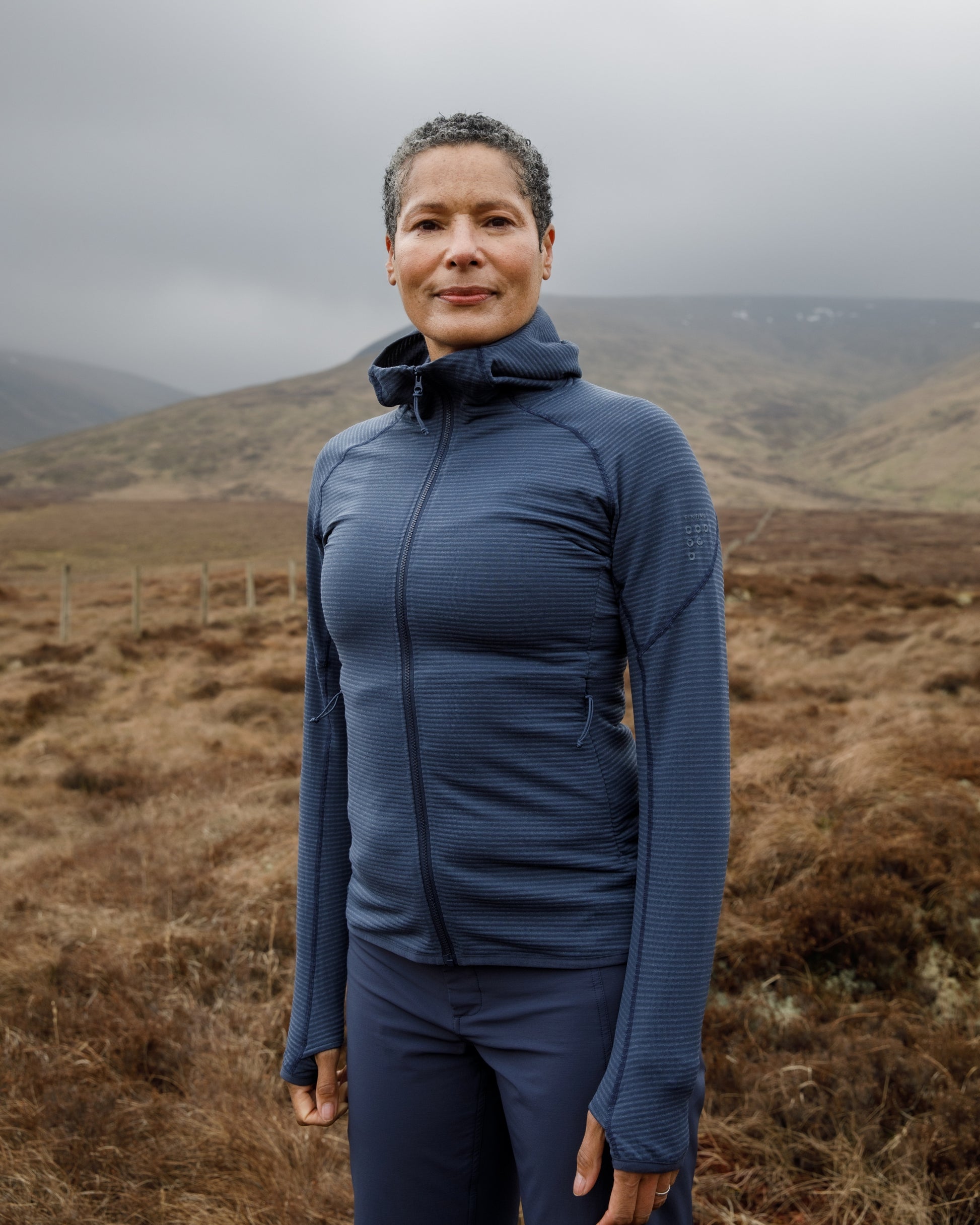Woman wearing a blue jacket standing in a mountainous landscape