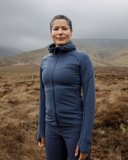 Woman wearing a blue jacket standing in a mountainous landscape
