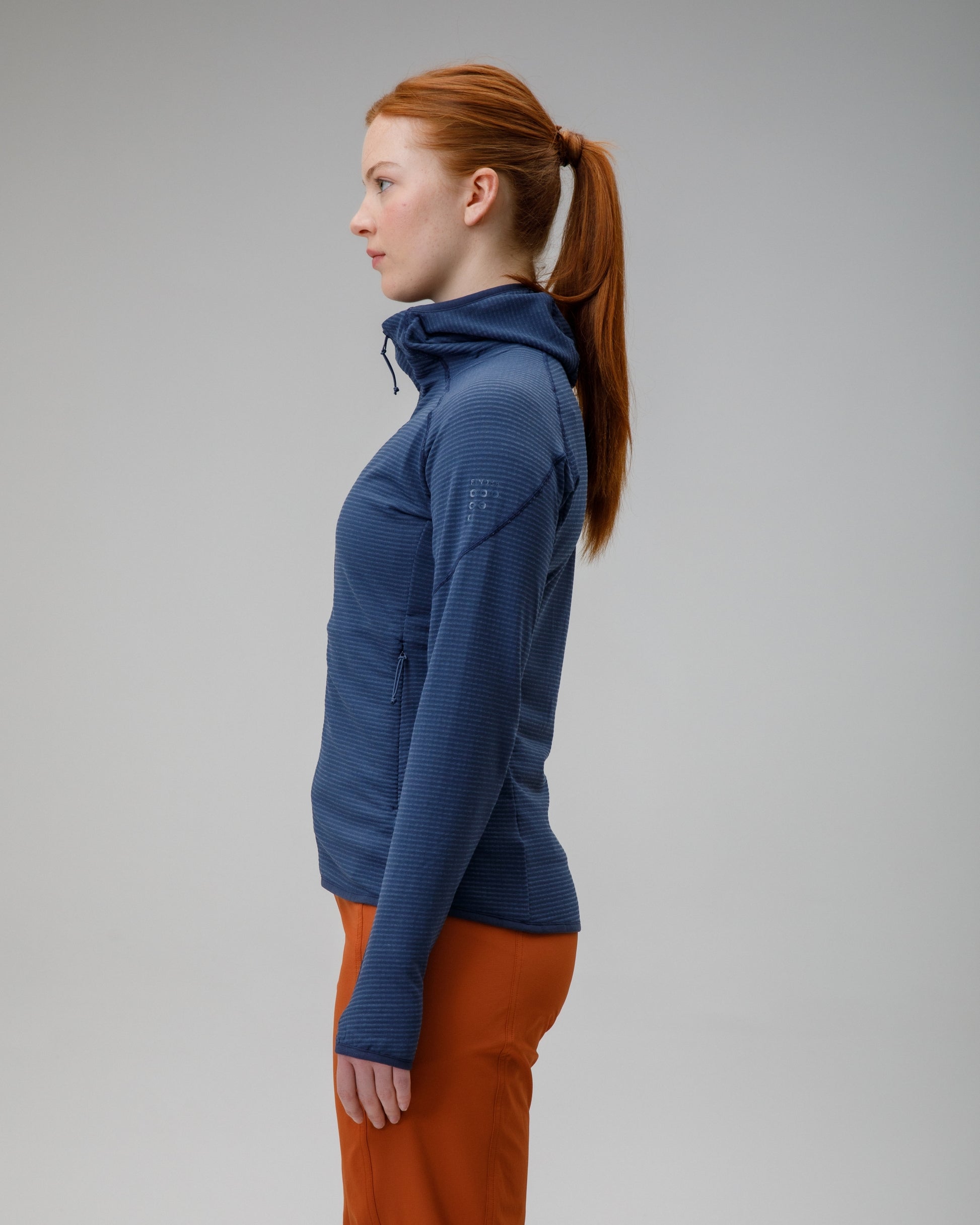 Person wearing a blue jacket and orange pants on a gray background