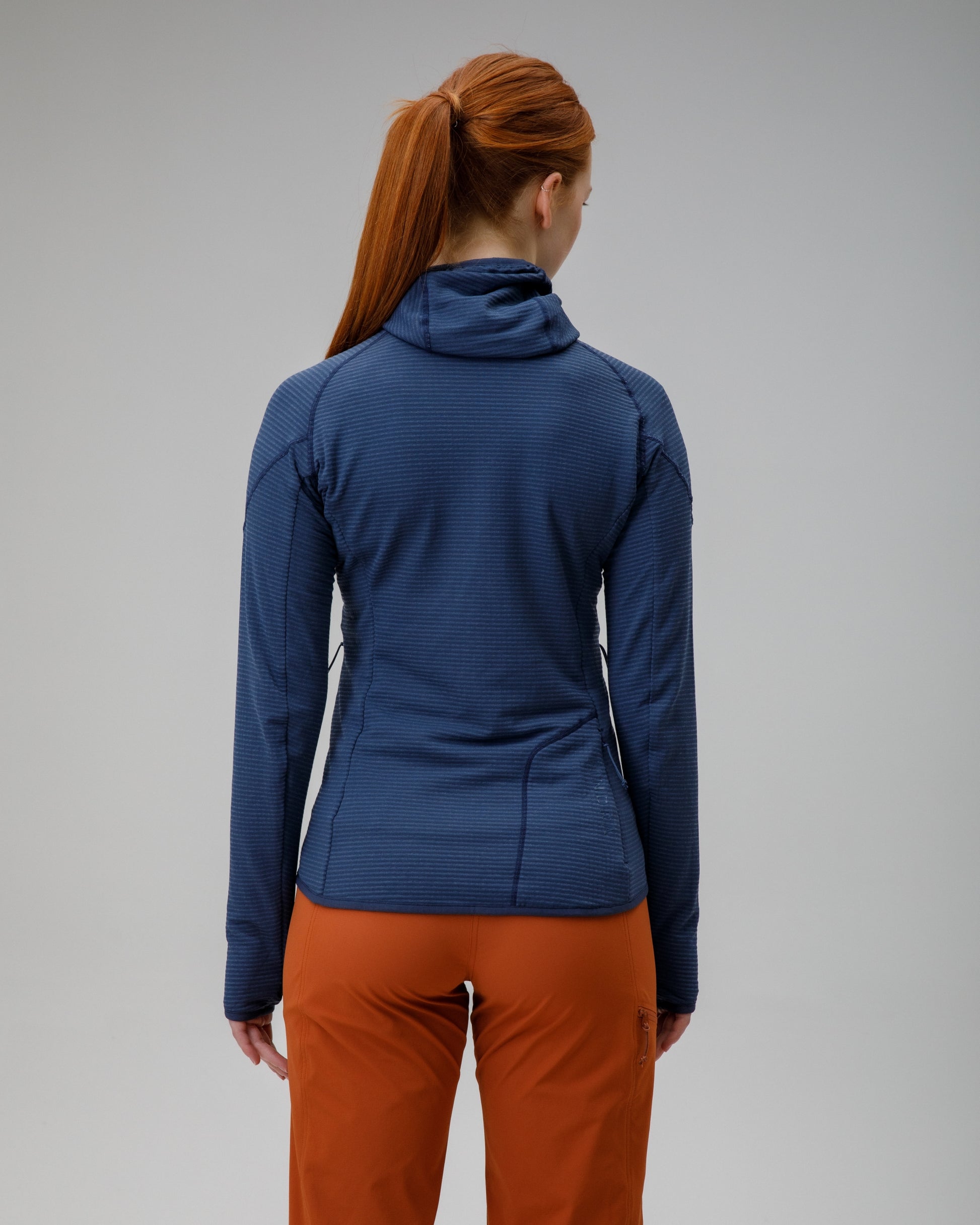 Person wearing a blue jacket and orange pants on a gray background