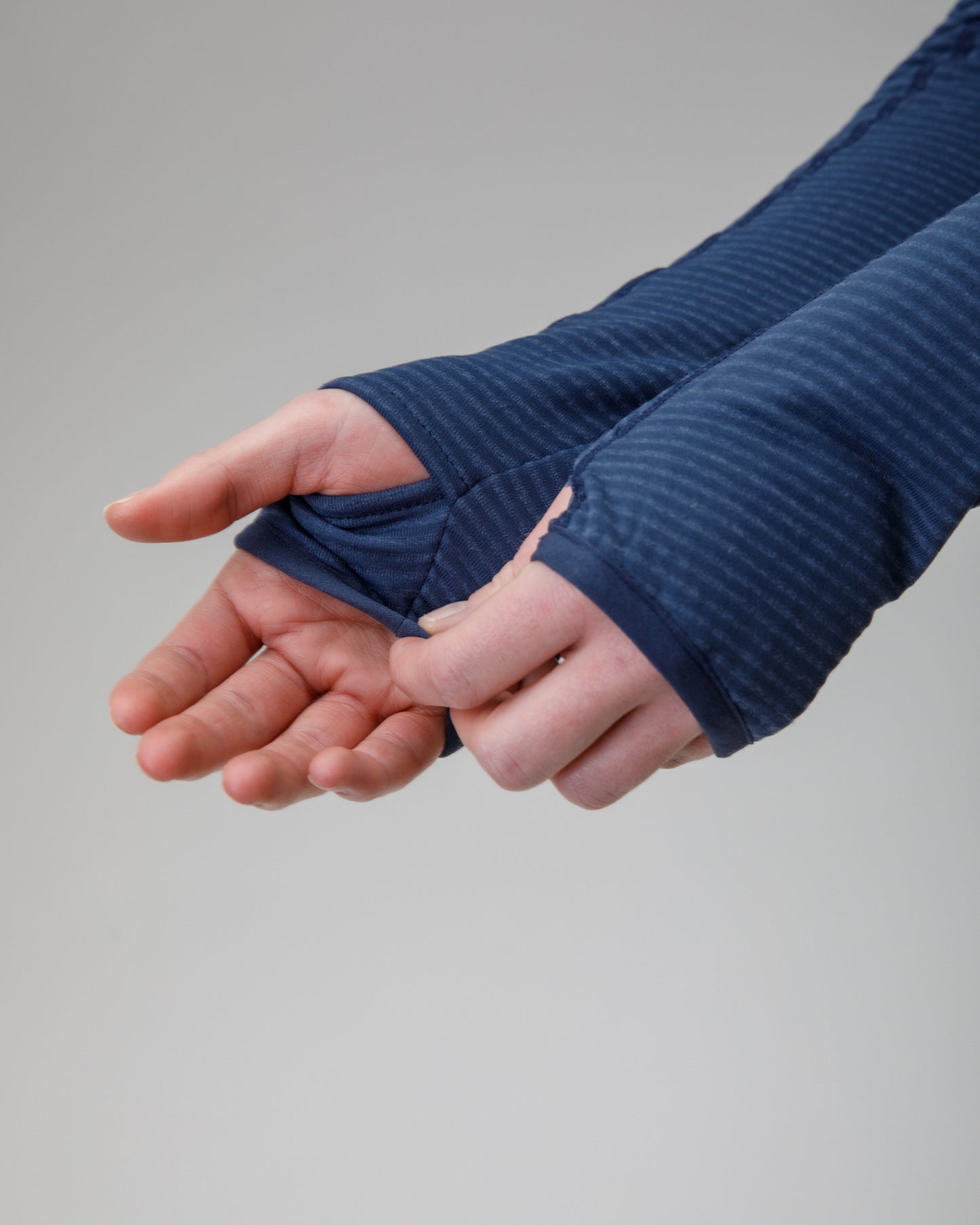 Person wearing a blue jacket showing the thumbholes on the sleeve 