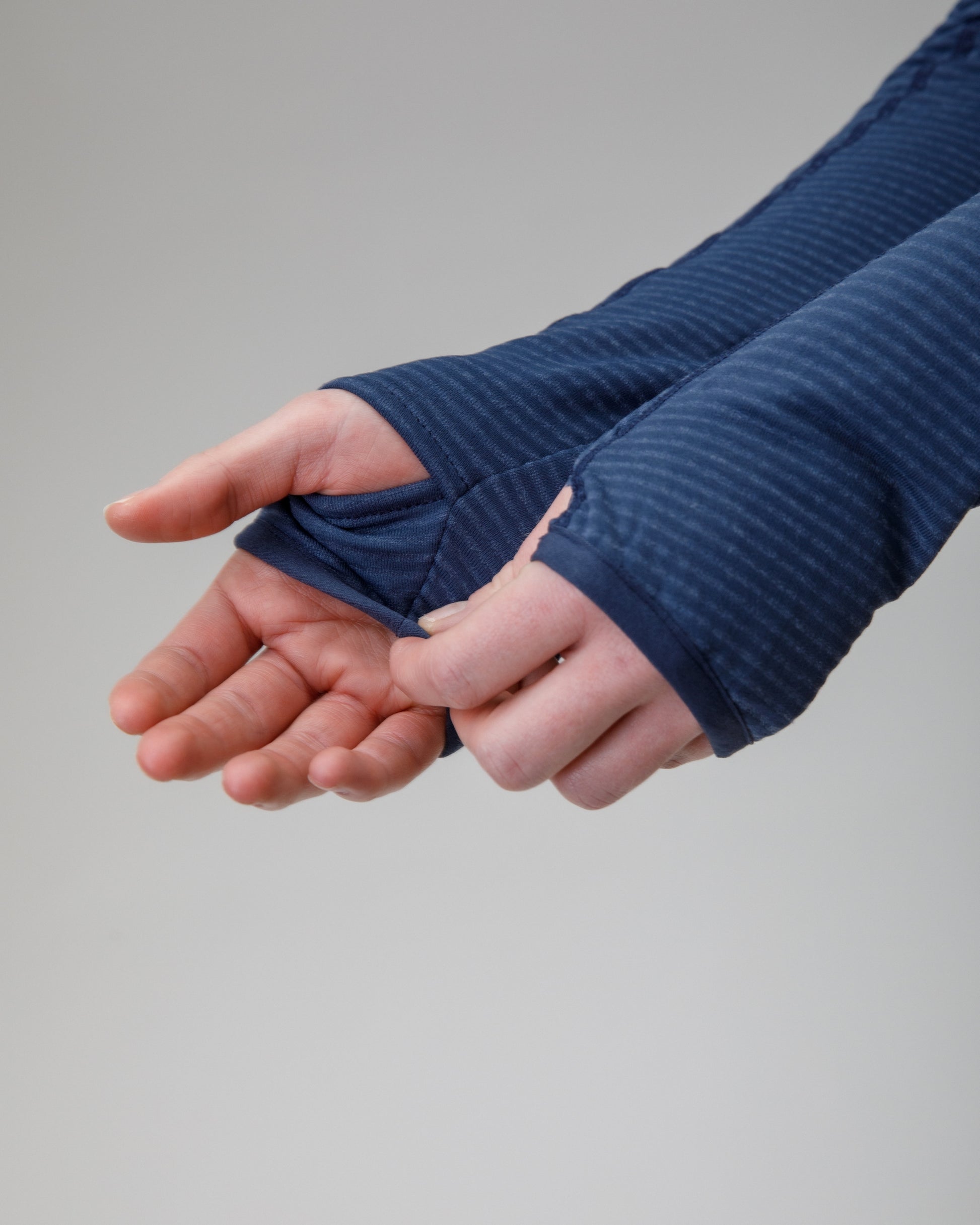 Person wearing a blue jacket showing the thumbholes on the sleeve 
