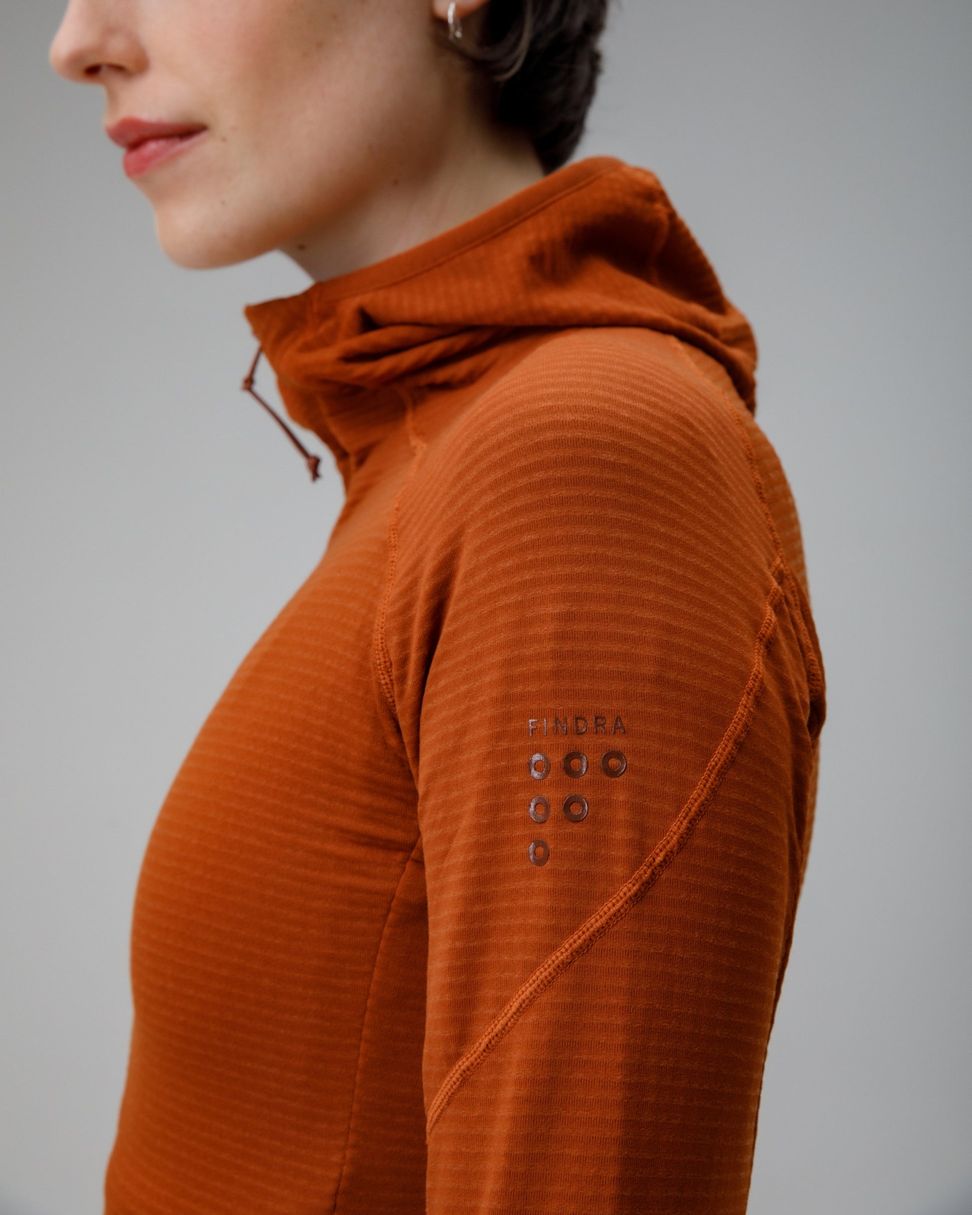 Person wearing a brown textured hoodie on a gray background