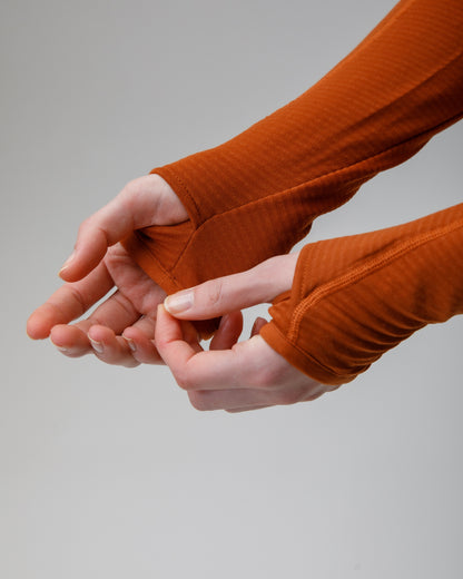 Close-up of hands wearing orange sleeves with thumbholes against a gray background