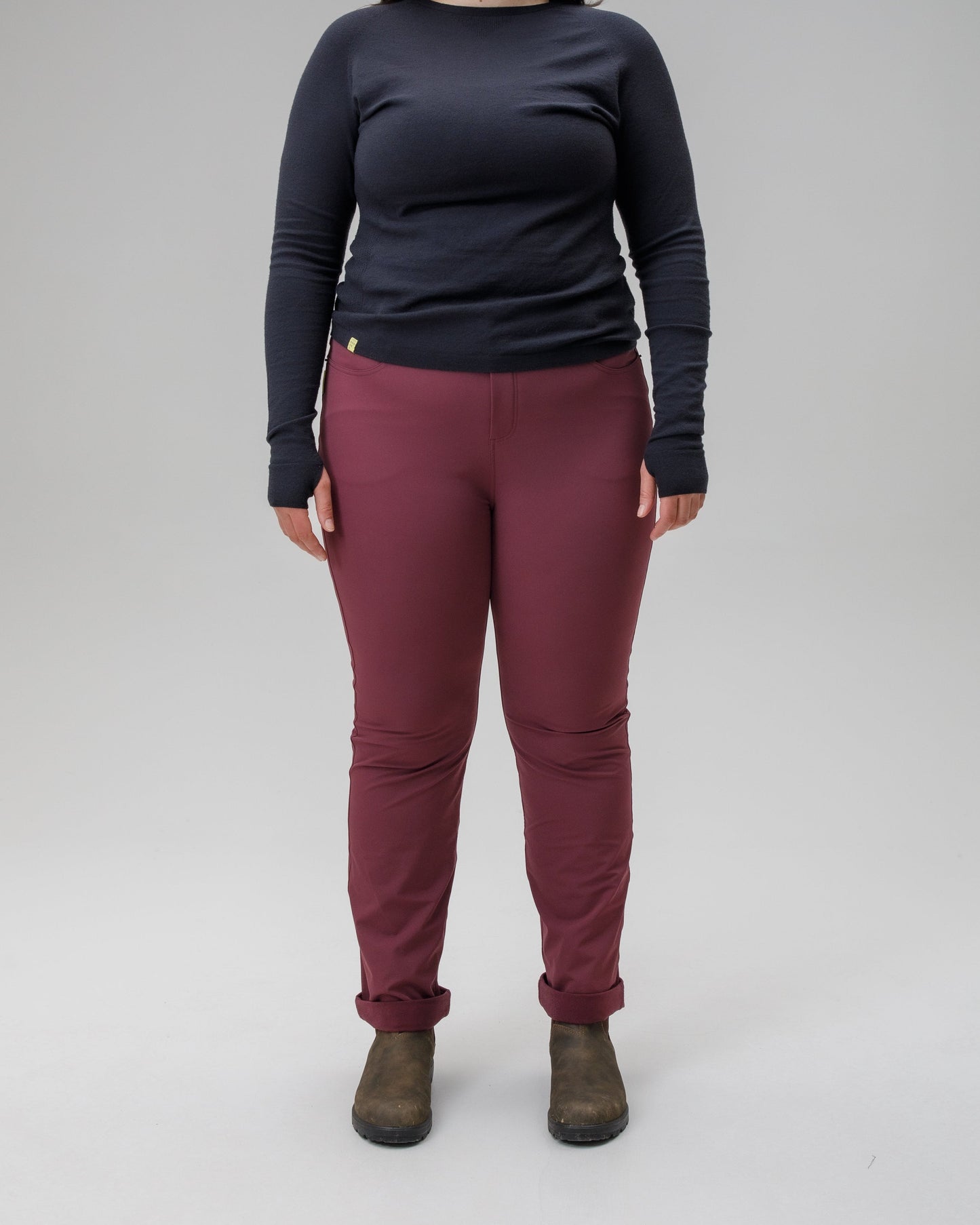 Person wearing a black long-sleeve top and maroon pants on a gray background