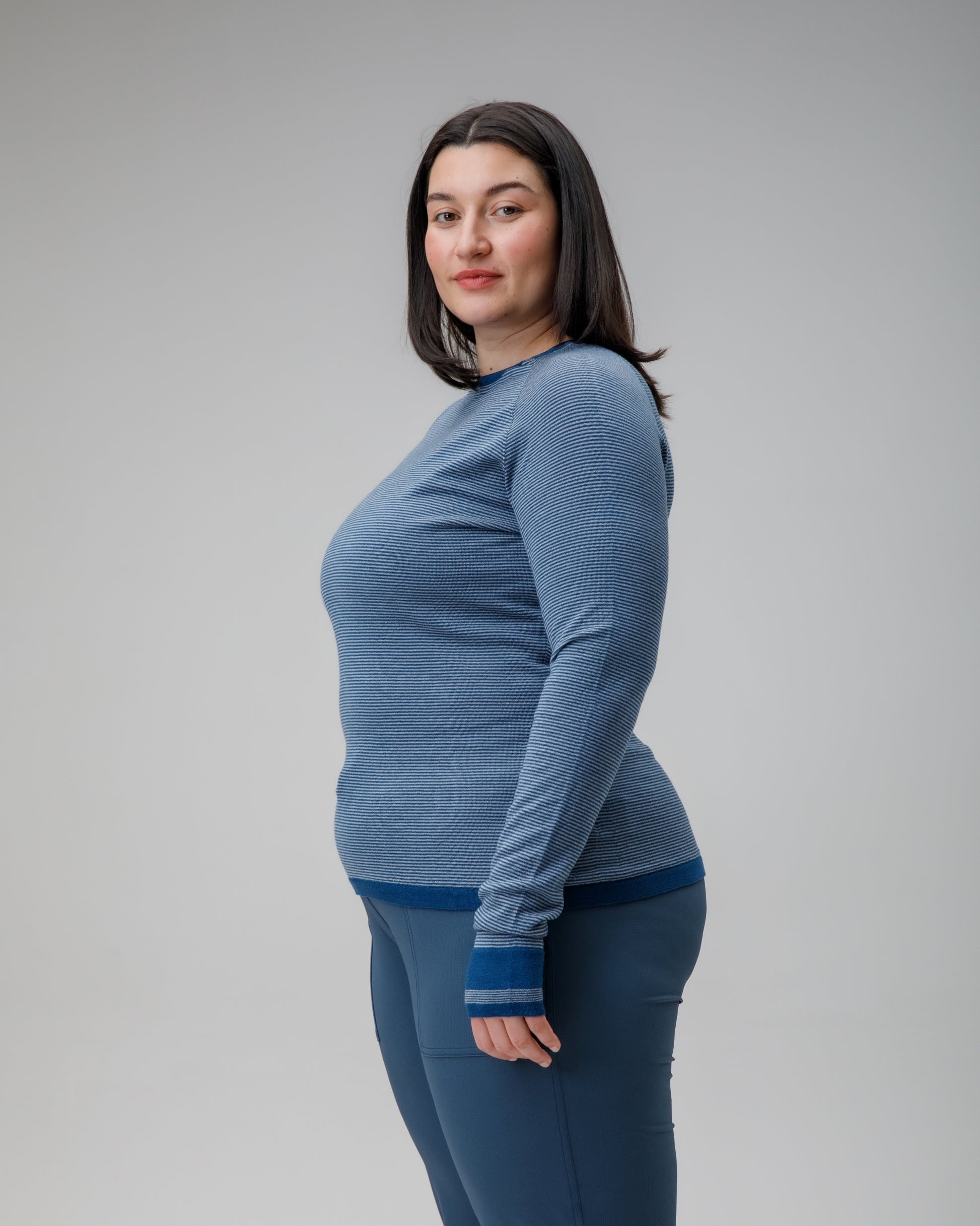 Woman wearing a blue long-sleeve top and leggings against a gray background
