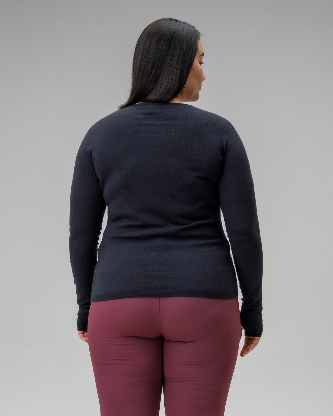 Person wearing a black long-sleeve top and maroon pants on a gray background