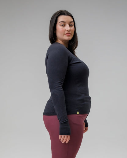 Woman wearing a dark long-sleeve top and maroon pants on a gray background