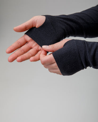 Person wearing black fingerless gloves on a gray background