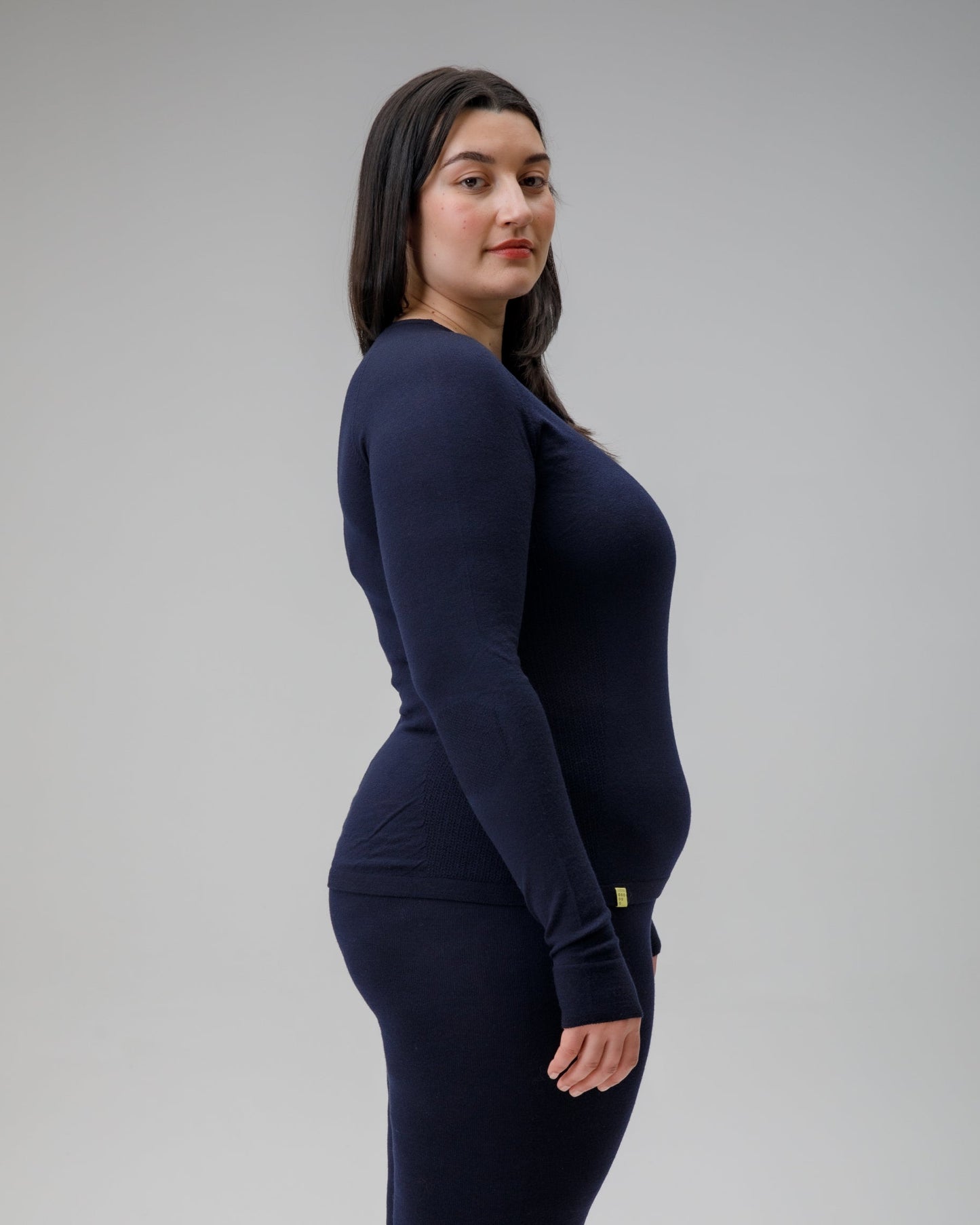 Woman wearing a navy long-sleeve top and pants on a gray background