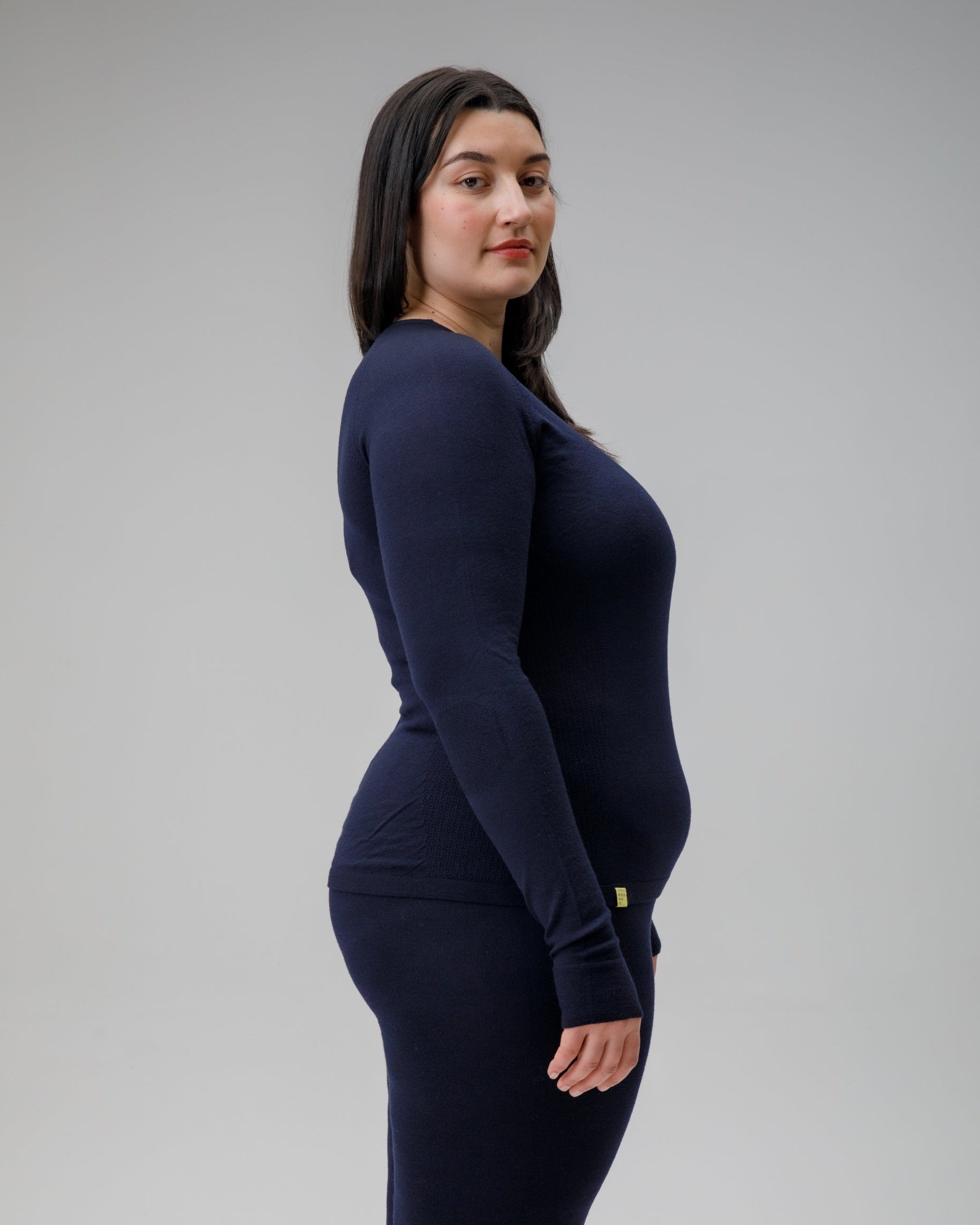 Woman wearing a navy long-sleeve top and pants on a gray background