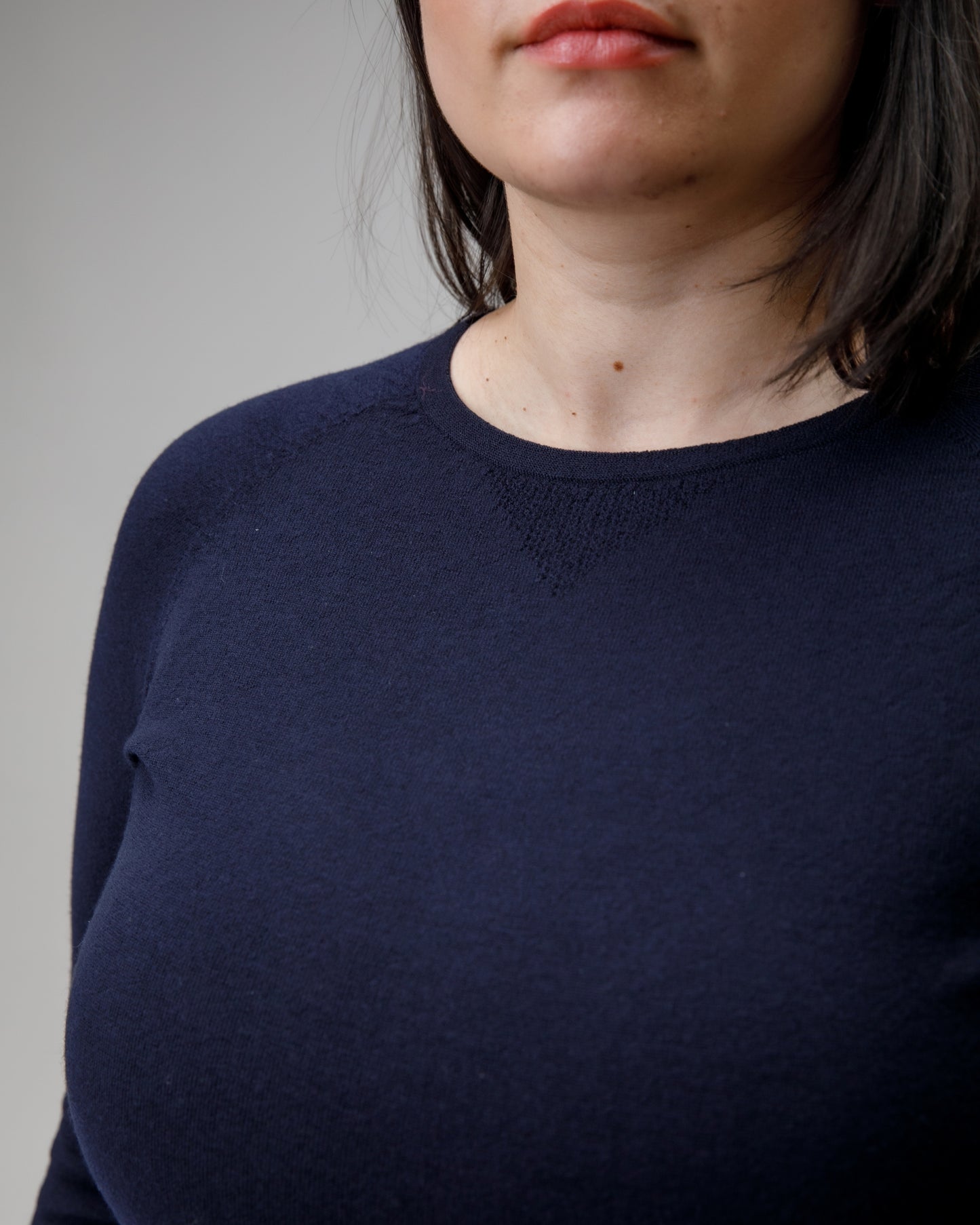 Navy blue sweater worn by a person on a gray background