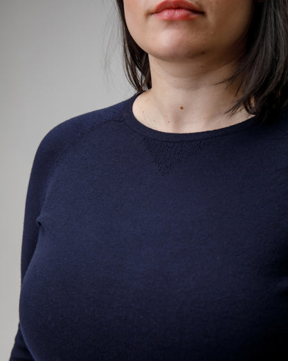 Navy blue sweater worn by a person on a gray background