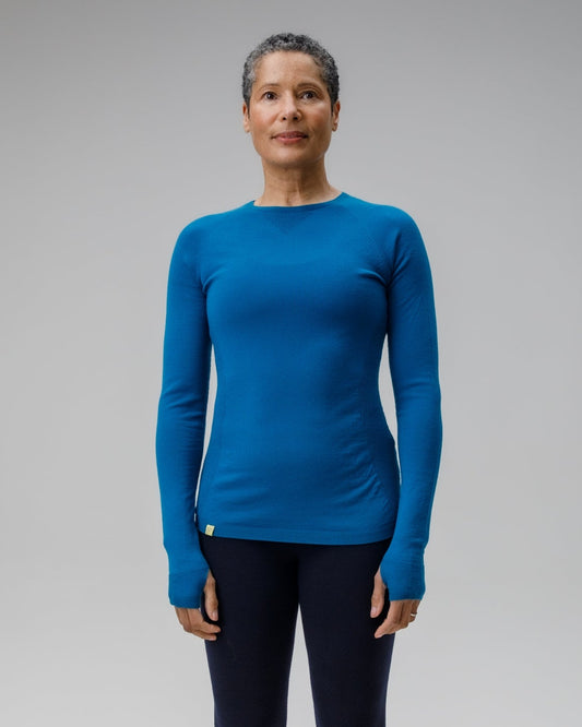 Person wearing a blue long-sleeve top and black leggings on a gray background
