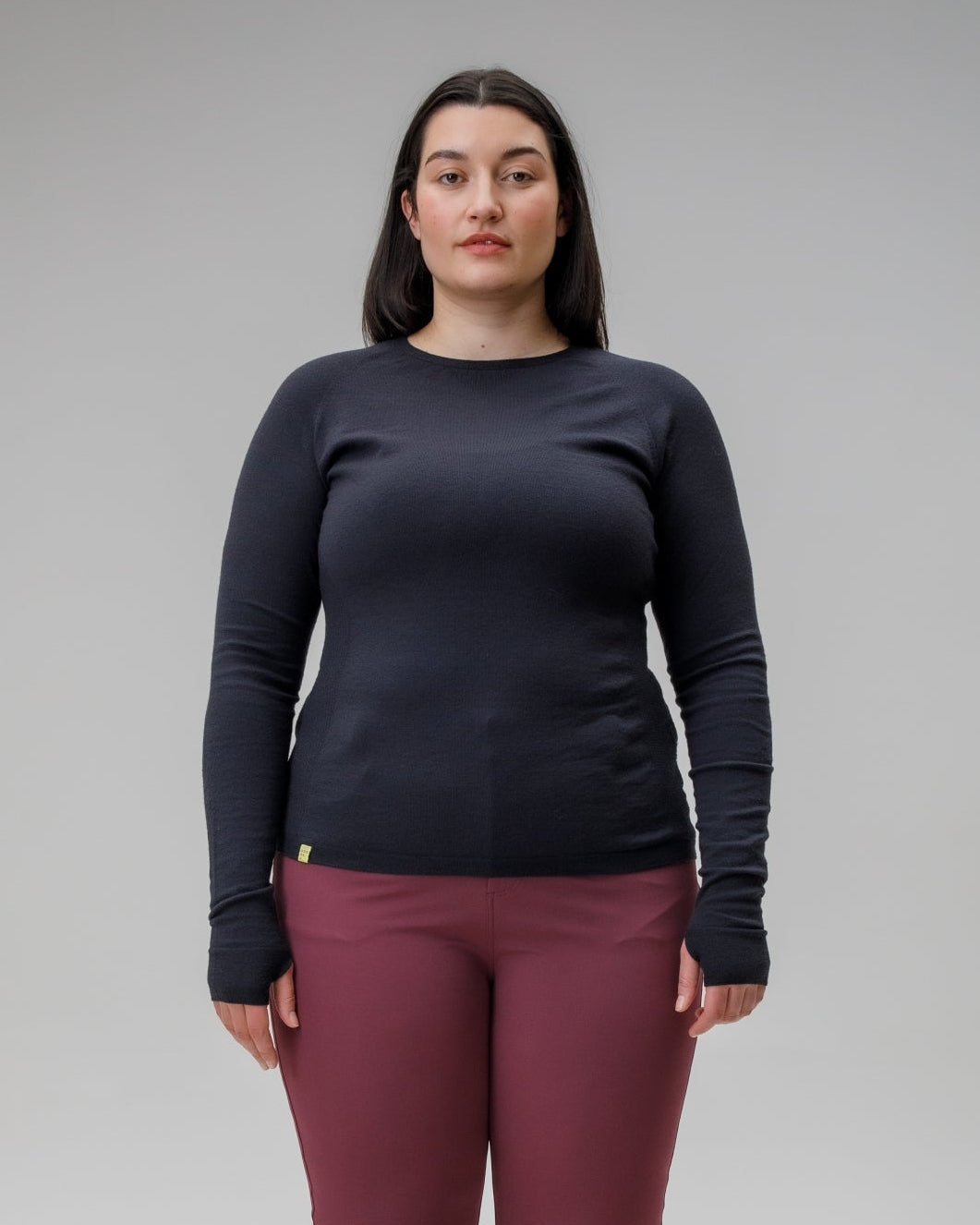 Person wearing a black long-sleeve shirt and maroon pants on a gray background